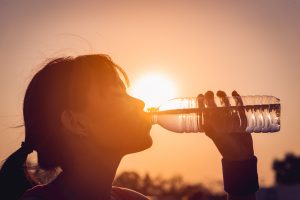 young woman drinking from a plastic water bottle outside