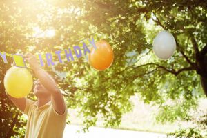 dad hanging "happy birthday" banner and balloons outdoors