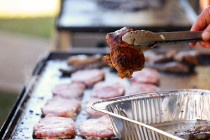 meat between tongs with grill in background